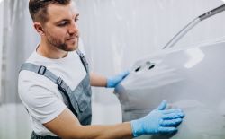 Mechanic fitting sheet metal before repairing a trailer