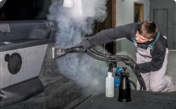 A truck wash employee disinfects the interior of a truck cab