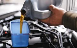 Mechanic's hand pouring engine oil from a container